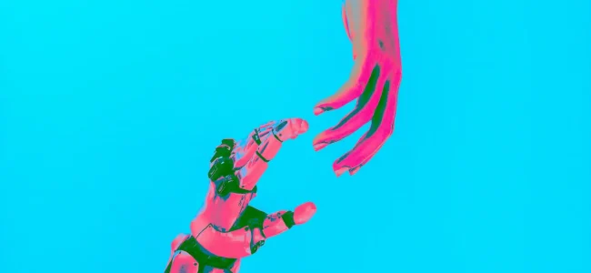 Eine künstliche Hand und eine menschliche Hand sind vor einem einfarbig blauen Hintergrund dargestellt. Beide Hände sind einander zugewandt und berühren sich nicht.